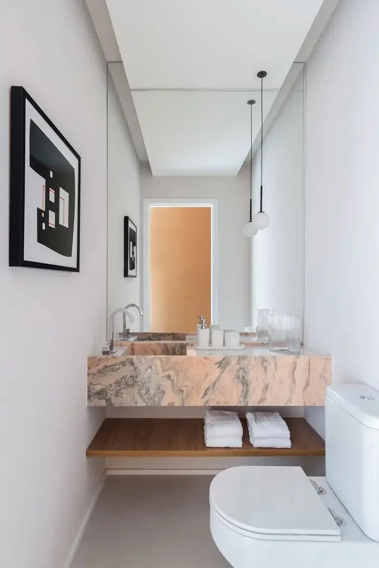 Lavabo com bancada e cuba esculpida em mármore Rosa Bahia, rosa com veios brancos e escuros, torneira cromada e espelho